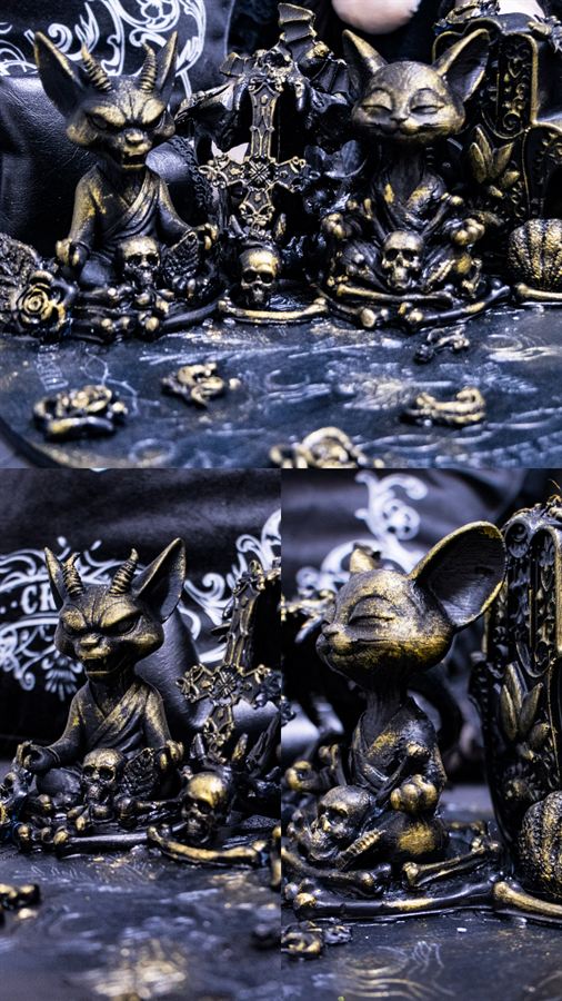 Katzenfiguren mit Hörnern auf einer Friedhofsszene mit Schädeln