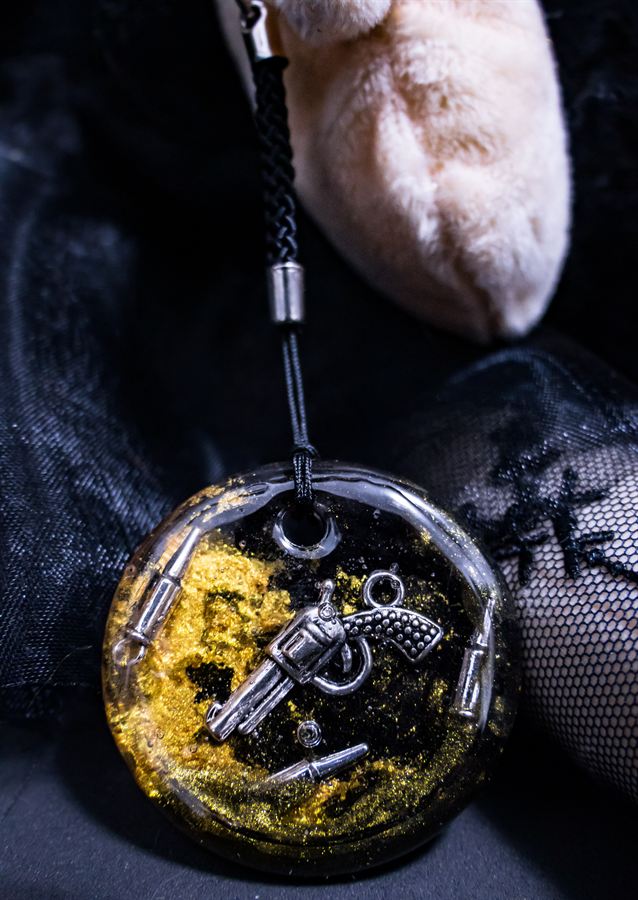 Runder Resin-Anhänger mit Revolver und Patronen auf Blattgold